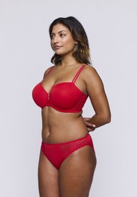 Rode lingerieset bestaande uit een gelifte bh met kanten accenten en verstelbare bandjes, gecombineerd met bijpassende slipjes met geschulpte details.