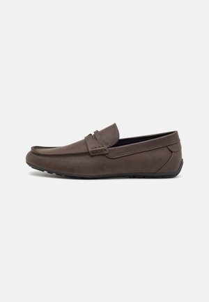 Mocassin marron en cuir à enfiler avec couture sur le bout mocassin et semelle en caoutchouc, présenté de profil sur un fond gris clair.