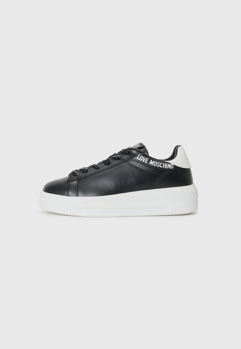 Zwarte leren sneaker met een witte zool, ronde neus en zwarte veters. Heeft witte "LOVE MOSCHINO" branding op de tong en hak.