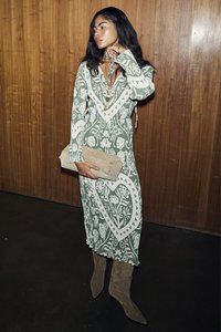 Μακριά πράσινη φόρεμα με λευκά λουλουδάτα σχέδια, με σύσφιξη στη μέση και μακριά μανίκια. Συνδυασμένο με μια μπεζ τσάντα και ταμπούχ μπότα μέχρι το γόνατο.