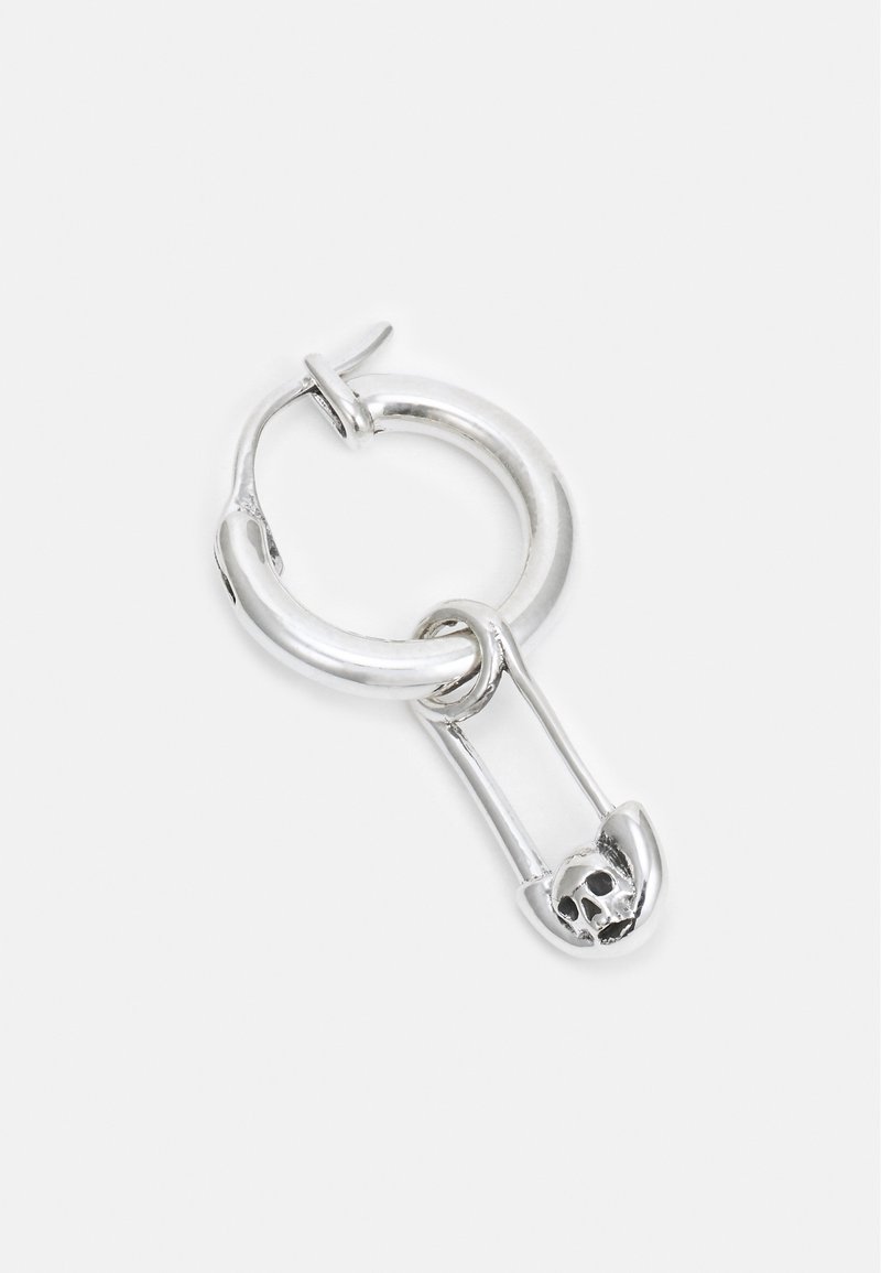 Créole en argent avec une épingle de sûreté suspendue avec un petit détail de crâne sur le fermoir de l'épingle.