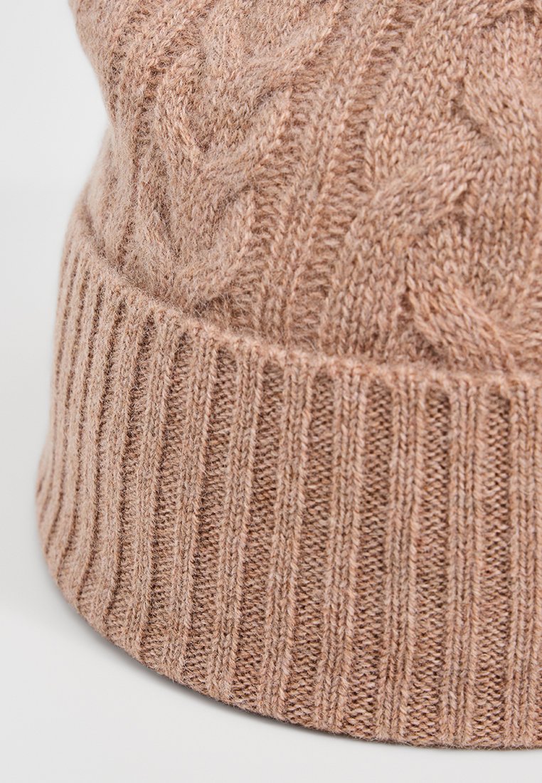 Beżowa dziana czapka z ribbowanym zagięciem i wzorem w warkocze na miękkiej, teksturowanej wełnie.