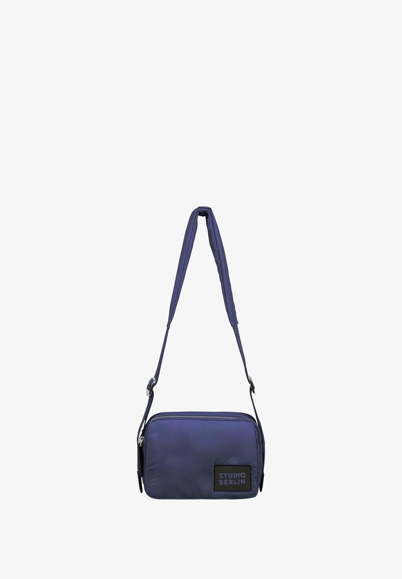 Jūras spēku krāsas plecu soma ar gludu neilona apdari, taisnstūra forma, regulējama siksna, rāvējslēdzējs un zīmola plāksne priekšpusē.