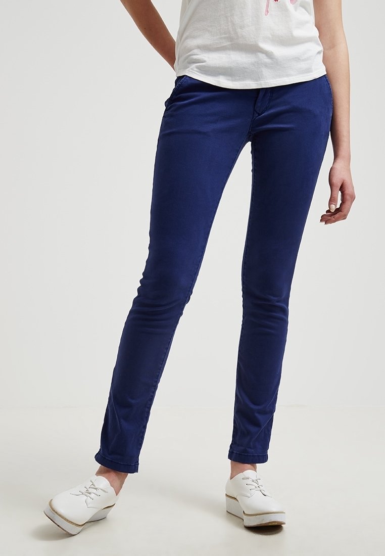 Pantalons en coton bleu marine, coupe slim, avec une texture lisse ; poches avant ; assortis à une chemise blanche à manches courtes et des chaussures blanches.
