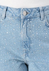 Φωτεινά μπλε τζιν παντελόνια με εφαρμοστή σχεδίαση, διακοσμημένα με ασημένιες ραβδώσεις σε διάσπαρτο σχέδιο στο μπροστινό μέρος.