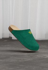 Groene instapklompen met een gestructureerd bovenwerk, kurken zool en een geel logo. Voorzien van een bloemmotief over het oppervlak.