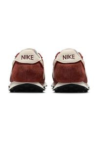 Sapatilhas de camurça vermelha com detalhes em branco, apresentando um colar acolchoado e uma sola de borracha preta texturizada. Logotipo da Nike exibido no calcanhar.