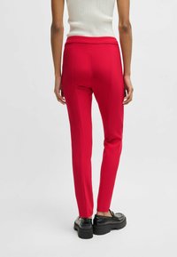 Pantaloni rossi su misura con una texture liscia, vestibilità slim e vita alta. Abbinali a scarpe con piattaforma nere per contrasto.