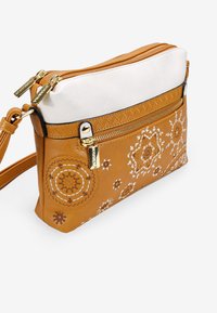 Bolso bandolera de cuero marrón con parte superior blanca, que presenta intrincados patrones bordados en blanco y marrón, herrajes en tono dorado y cierres con cremallera.