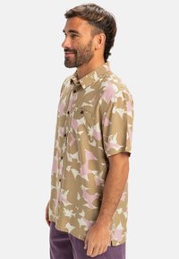 Kurzärmliges Hemd mit Knopfleiste in beige mit rosa und weißen abstrakten Mustern, ausgestattet mit einer Brusttasche und einem lockeren Schnitt.