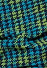 Textil mit einem geometrischen Hahnentrittmuster in Blau, Grün und Schwarz. Der Stoff zeigt eine strukturierte, gewebte Oberfläche.