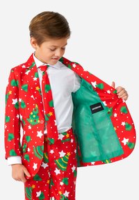 Completo per le festività in rosso, con fantasie di alberi di Natale e stelle verdi. Presenta una giacca a un bottone e una cravatta abbinata; il rivestimento interno è turchese.