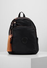 Schwarzer Rucksack mit Fronttasche, rosa-goldenen Reißverschlüssen, rundem Logo und einem hellbraunen Quasten-Schlüsselanhänger auf einer weißen Oberfläche.