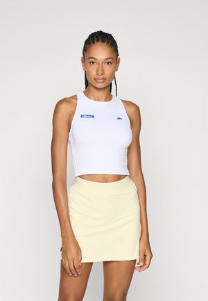 White crop top with blue logo, paired with a light yellow skirt. The top features a round neck and racerback design, while the skirt has a smooth texture.