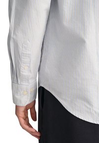 Lichtblauw en wit gestreept katoenen shirt met knoopmanchetten, gebogen zoom en een soepele textuur, gedragen over donkere stof.