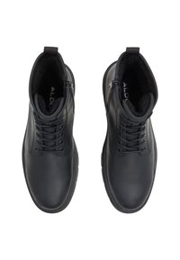 Botas de tobillo de cuero negro con una textura suave, puntera redonda, parte delantera con cordones y cremallera lateral, con un interior acolchado.