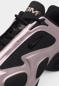 Close-up of a black and pink Nike sneaker featuring the AM 97 logo, textured mesh, and black laces.