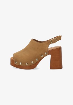 Clogs en daim marron à bout ouvert avec une large sangle et une boucle. Le talon en bois est épais et présente des accents métalliques sur le côté pour des détails.