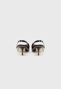 Zwarte hoge hakken sandalen van glad materiaal, open achterkant en dunne enkelband. Beschikt over een taps toelopende hak en een lichte, beige zool.