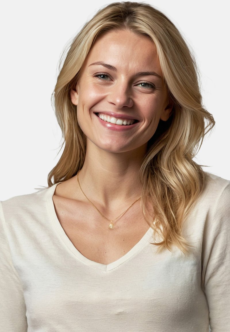 Guldhalskæde med en cirkulær vedhæng båret over en lysefarvet, blød V-hals skjorte. Baggrunden er ensfarvet hvid.