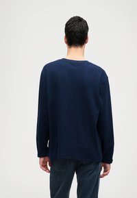 Námornícka dlhá rukávová košeľa z texturovanej látky, s kruhovým výstrihom, vo voľnom strihu, s mierne spustenými ramenami a rovnými lemami.