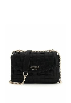 Sac à main matelassé noir de la marque Guess avec une bandoulière en chaîne argentée et une plaque logo sur le rabat avant, posé sur un fond blanc.
