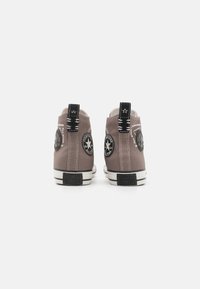 Gray high-top sneakers made of canvas, featuring black accents, white stitching, and round logo patches on each side. Rubber soles.