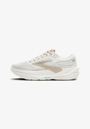 Baskets de course beige clair avec une tige en maille texturée, des accents en plastique lisse et une épaisse semelle blanche. Présente un laçage minimum et un branding discret.