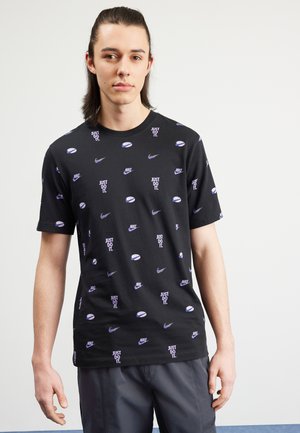 Camiseta de algodón negra con un patrón repetido de varios logotipos de Nike y la frase "JUST DO IT". Diseño de mangas cortas y cuello redondo.