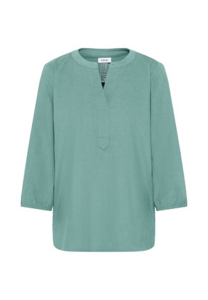 Blusa verde chiaro a maniche lunghe con scollatura rotonda e spacco a V frontale, polsini elasticizzati e vestibilità ampia.