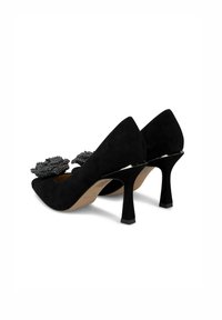 Scarpe con tacco alto in camoscio nero con punta affusolata, caratterizzate da un accento floreale decorativo in perline nere sulla tomaia e un tacco affusolato.