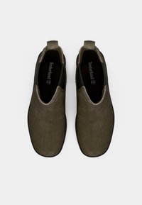 Bottes slip-on en suède vert olive avec une texture lisse, des panneaux latéraux élastiques noirs et un design à bout rond. Logo Timberland à l'intérieur.