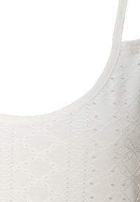 Witte tanktop met een textuurpatroon met ruitvormen en kleine perforaties, afgewerkt met smalle bandjes en een ronde halslijn.