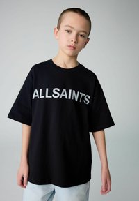 Juodas medvilninis marškinėliai trumpomis rankovėmis, su dideliu baltu užrašu "ALLSAINTS" krūtinėje. Derinama su šviesiomis džinsinėmis kelnėmis.