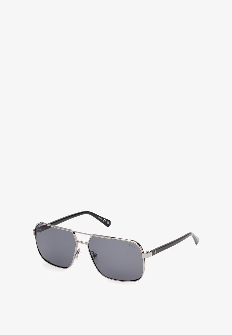 Ochelari de soare tip aviator din metal cu lentile gri, cadru argintiu și brațe negre. Au un design elegant cu un detaliu proeminent al punții nazale.