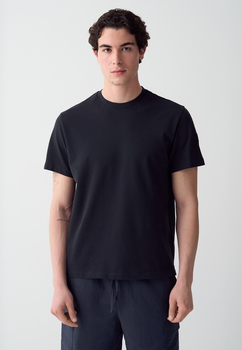 T-shirt nera a maniche corte con un design semplice e colletto rotondo. Realizzata in tessuto morbido, presenta una vestibilità comoda e senza motivi visibili.