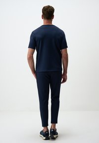 Camicia blu navy a maniche corte e pantaloni affusolati, realizzati in un tessuto morbido. Presenta un design semplice con scollo rotondo e dettagli di cucitura sottili.