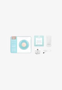 Foreo UFO mini, sirkulært apparat i lys blå med en teksturert overflate, ledsaget av en ansiktsmaske, USB-lader og instruksjonshefte.