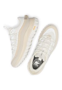 Valkoiset ja beige tennarit, joissa verkko- ja kumimateriaaleja, paksu pohja, pyöreä muoto, näkyvät nauhat ja brändilogolla varustettu kielen osa.