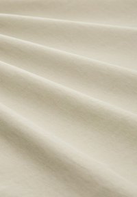 Lichtbeige stof met een gladde textuur, die subtiele plooien en een eenvoudig ontwerp toont. Zacht, valt gemakkelijk met een lichte glans.