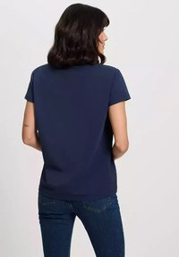 Granatowa koszulka z krótkim rękawem o luźnym kroju, gładkiej teksturze i okrągłym dekolcie. Widok z tyłu pokazuje prosty, niezdobiony fason.