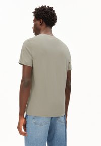 Gray cotton t-shirt with short sleeves, crew neck, and a relaxed fit; paired with light blue jeans, showing minimal detailing.