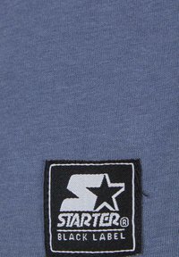 Blue fabric with a fine ribbed texture featuring a black and white "Starter Black Label" logo patch prominently displayed.