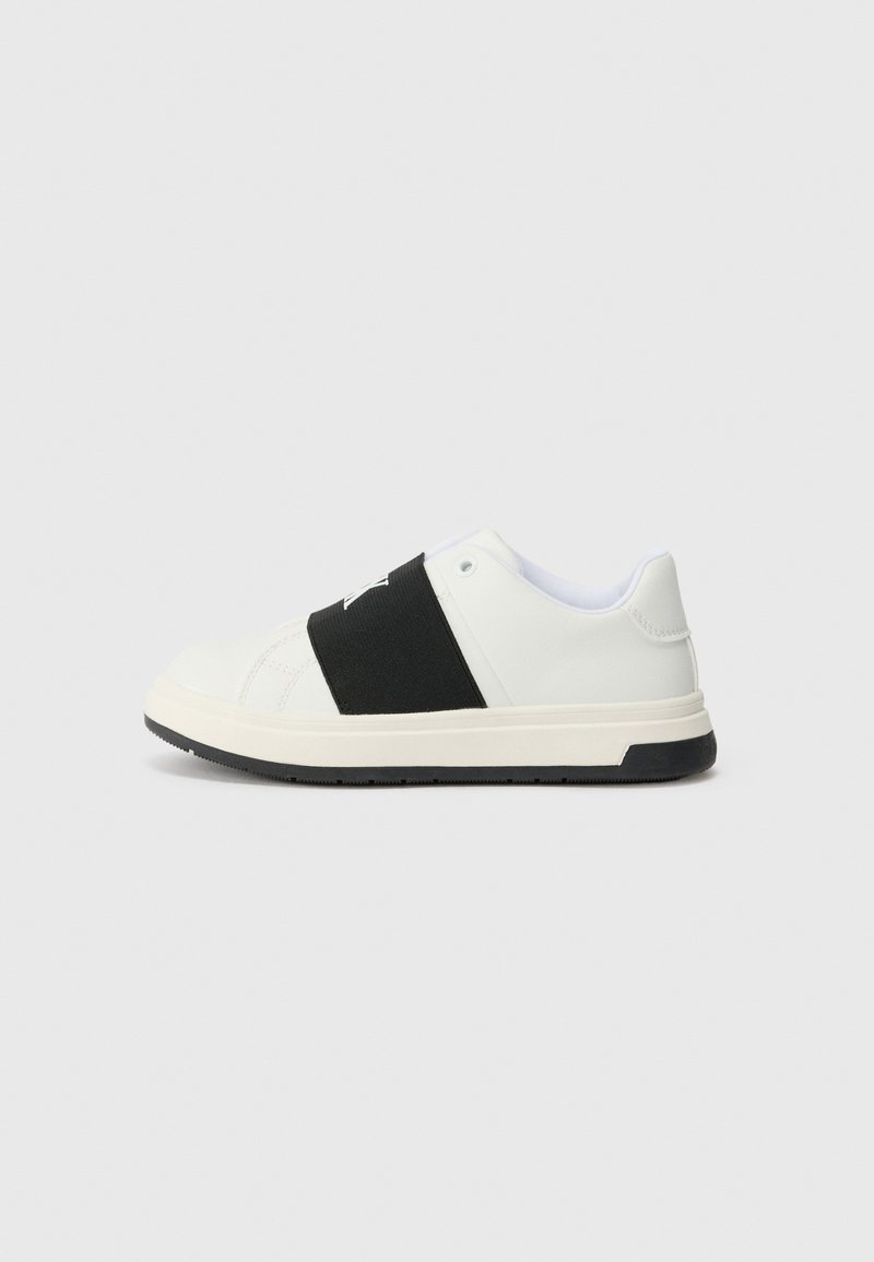 Hvite sneakers med et svart elastisk bånd over midtfoten, textured skinnøvre, og en gummisåle med et svakt mønster.