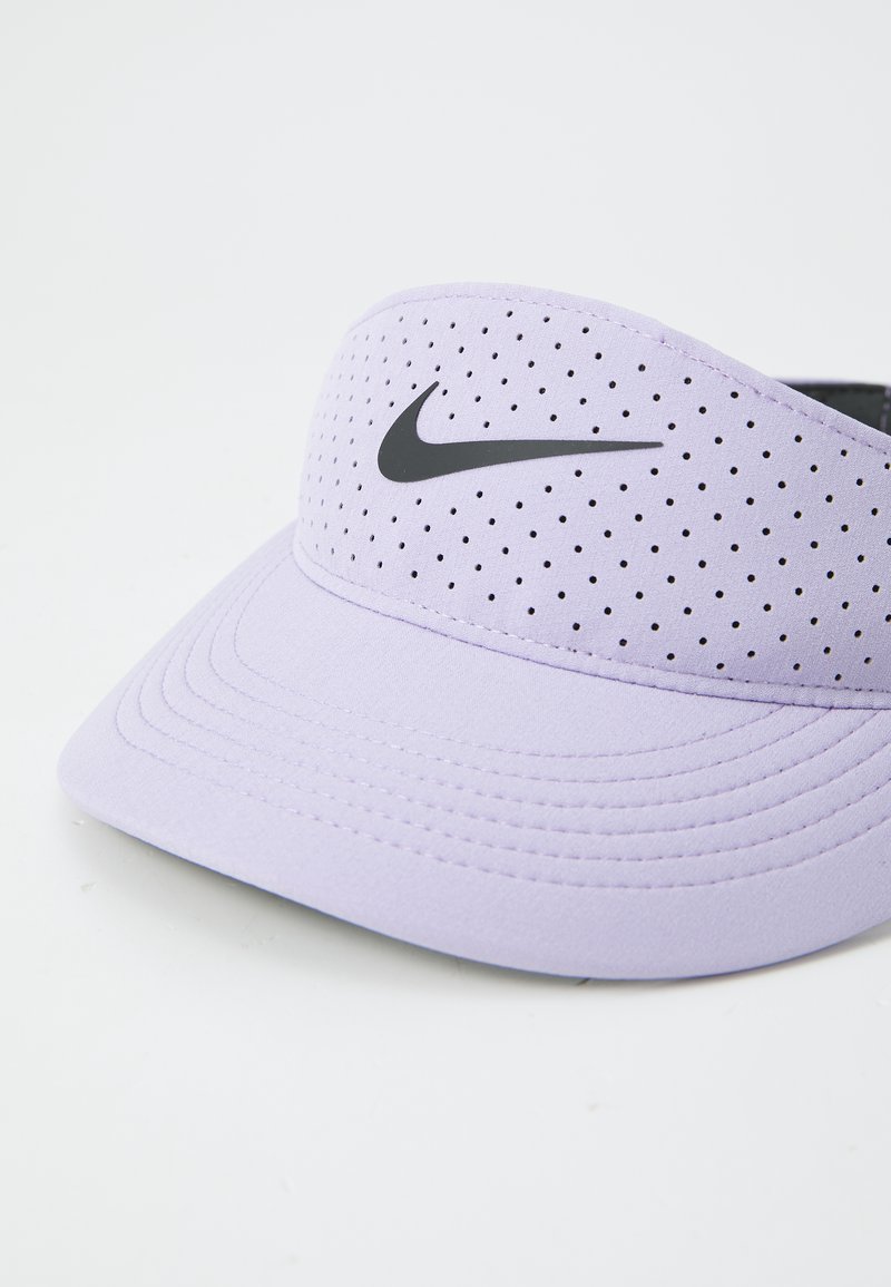 Casquette visière lilas en tissu lisse, ornée d'un logo Nike noir et de détails perforés pour la ventilation. Design de visière courbée.