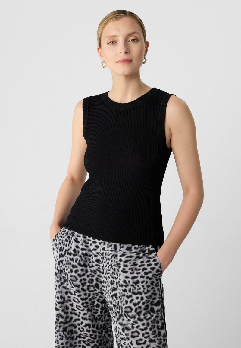 Top in maglia nera aCostine con scollatura rotonda, abbinato a pantaloni grigi con stampa leopardata e tasche laterali. Aggiornamento su abbigliamento casual.