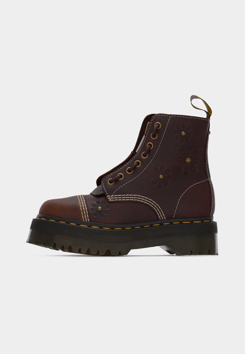 Dark brown leather lace-up boot with thick black sole, yellow stitching, floral embossing, and a pull tab at the back.