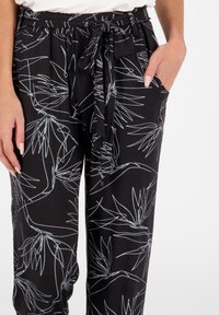 Schwarze Hosen aus leichtem Stoff, mit einem weißen botanischen Druck, elastischem Bund mit Kordelzug und Seitentaschen.
