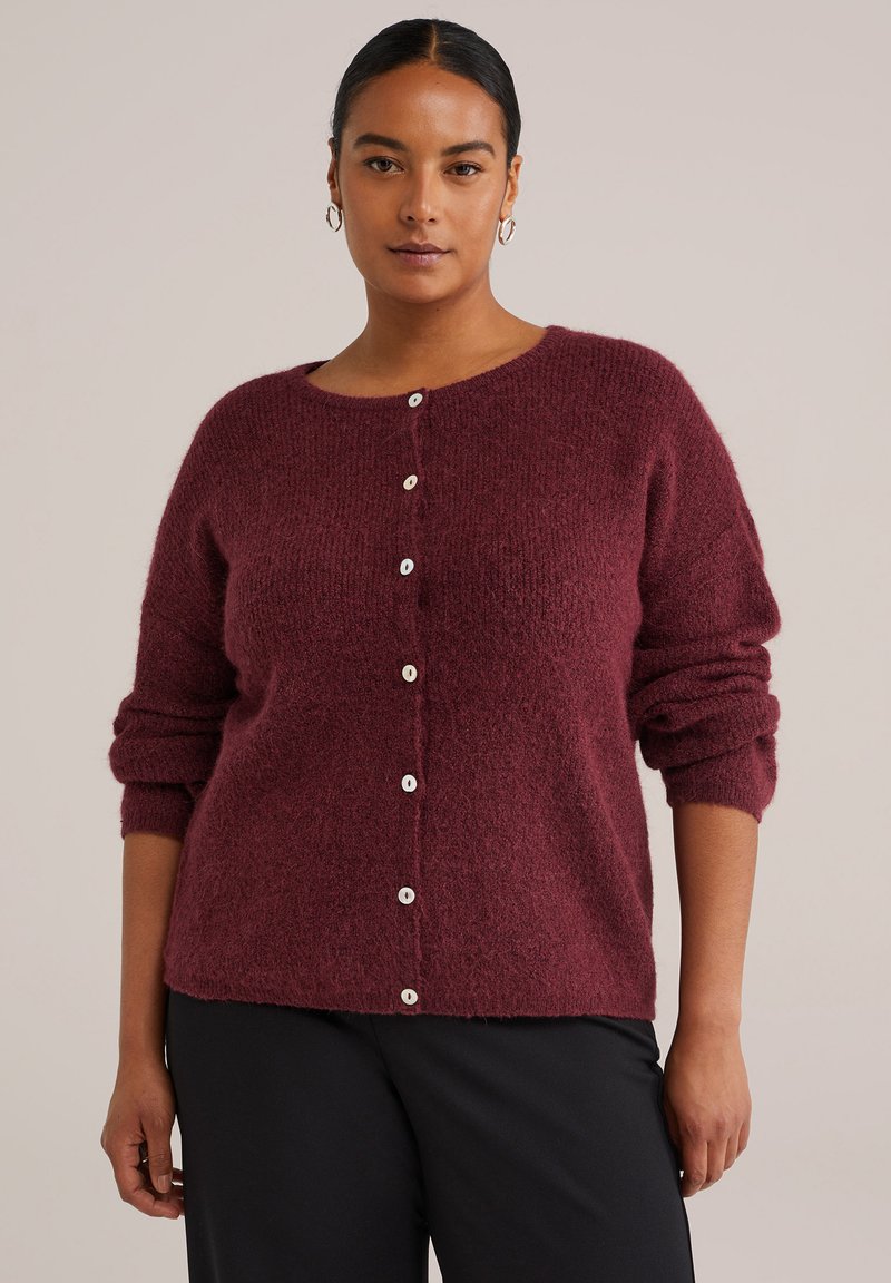Burgundy stickad cardigan med lös passform, rund halsringning och vita knäppningar fram. Mjuk textur och upprullade ärmar.