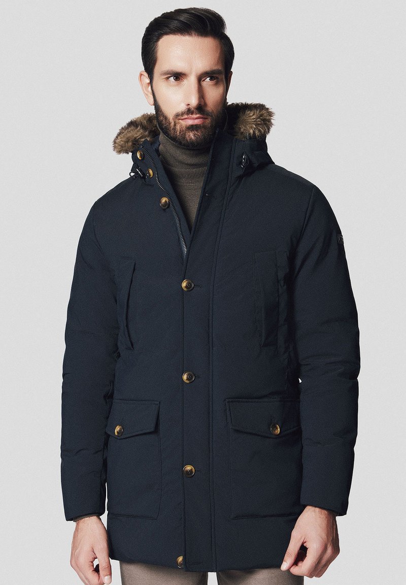 Granatowa ocieplana parka z futrzanym kapturem, z metalowymi guzikami w kolorze złotym, dwoma przednimi kieszeniami i zamek błyskawicznym z przodu. Teksturowana tkanina.